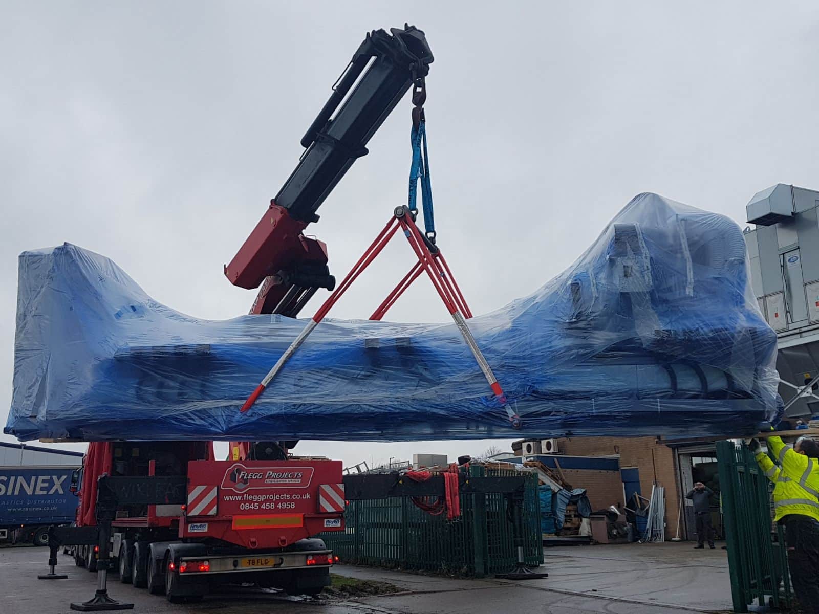 Red crane lifting large blue equipment